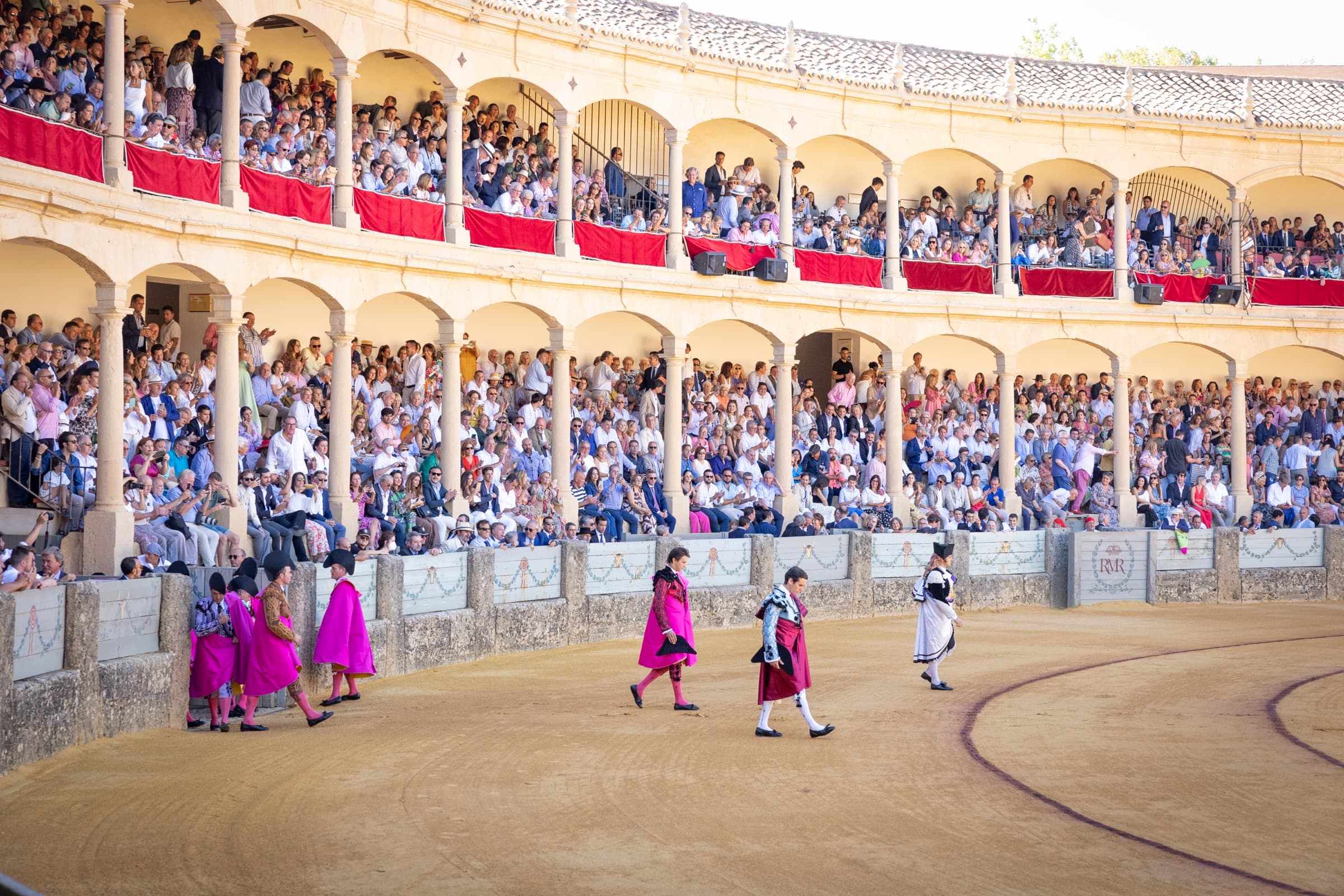 La doble galería de arcos de la plaza de toros de Ronda, llena de público durante el paseíllo de la Corrida Goyesca