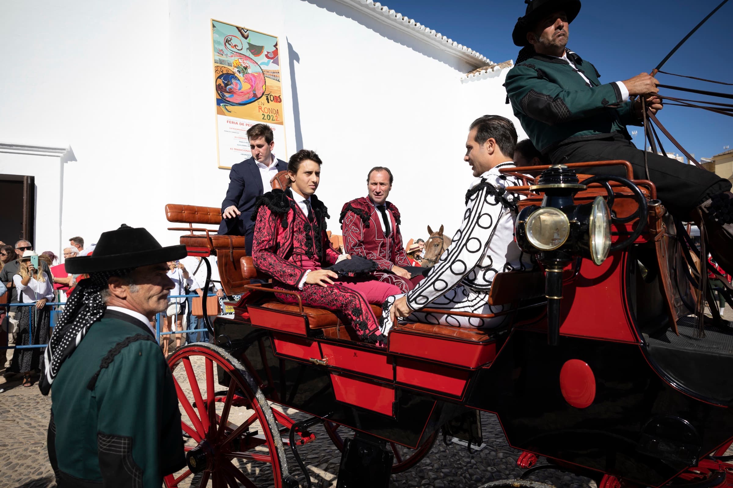 Los toreros llegan en calesa a la plaza de Ronda, junto al cartel de la Feria de Pedro Romero