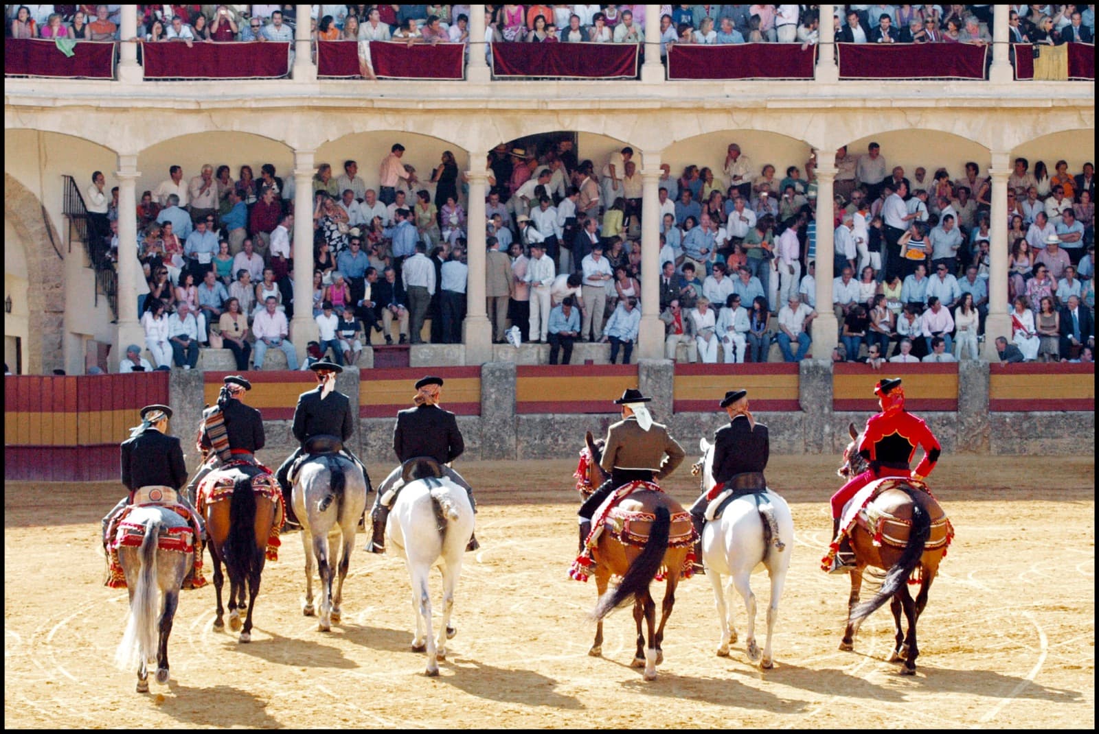 Un grupo de jinetes con indumentaria goyesca, formado en el ruedo frente a la doble galería llena de público, en la Goyesca de 2005