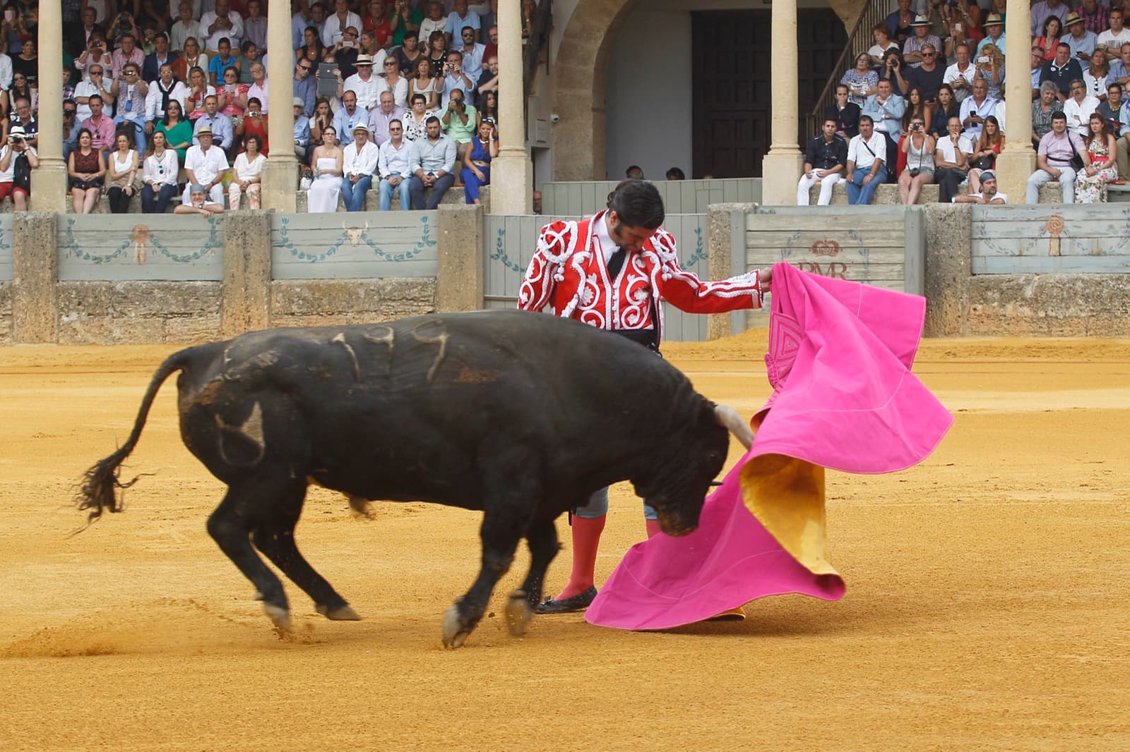 Morante de la Puebla, con traje goyesco rojo, recibe al toro con el capote en la Goyesca de 2015